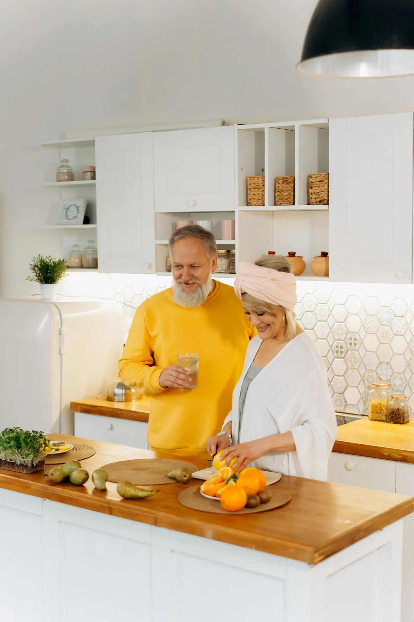 An older couple preparing fresh food together in a bright white kitchen