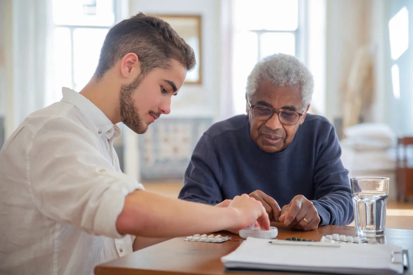 A younger man and an older man working on a familiar activity at a table